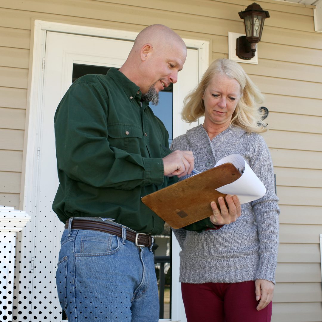 A home inspector reviews the inspection report with the homeowner using a clipboard. 