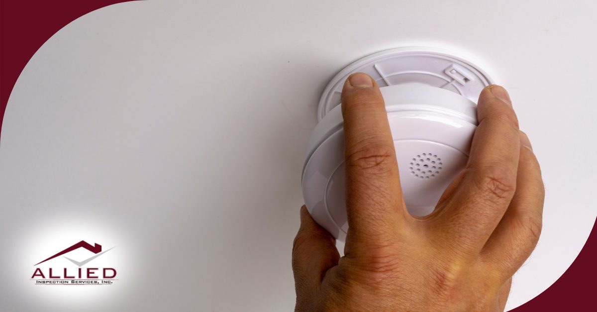 Hand pressing the button on a smoke detector.