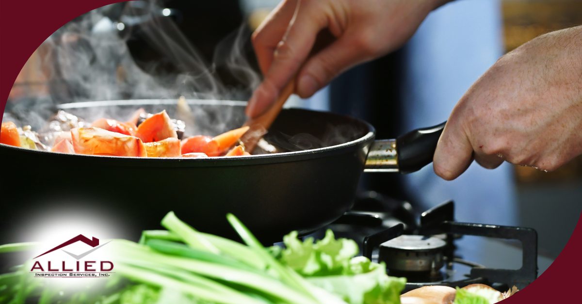 Close-up of vegetables being stirred in a frying pan with steam rising, while fresh ingredients are on the counter.