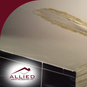Ceiling with severe water damage and peeling paint near bathroom tiles.
